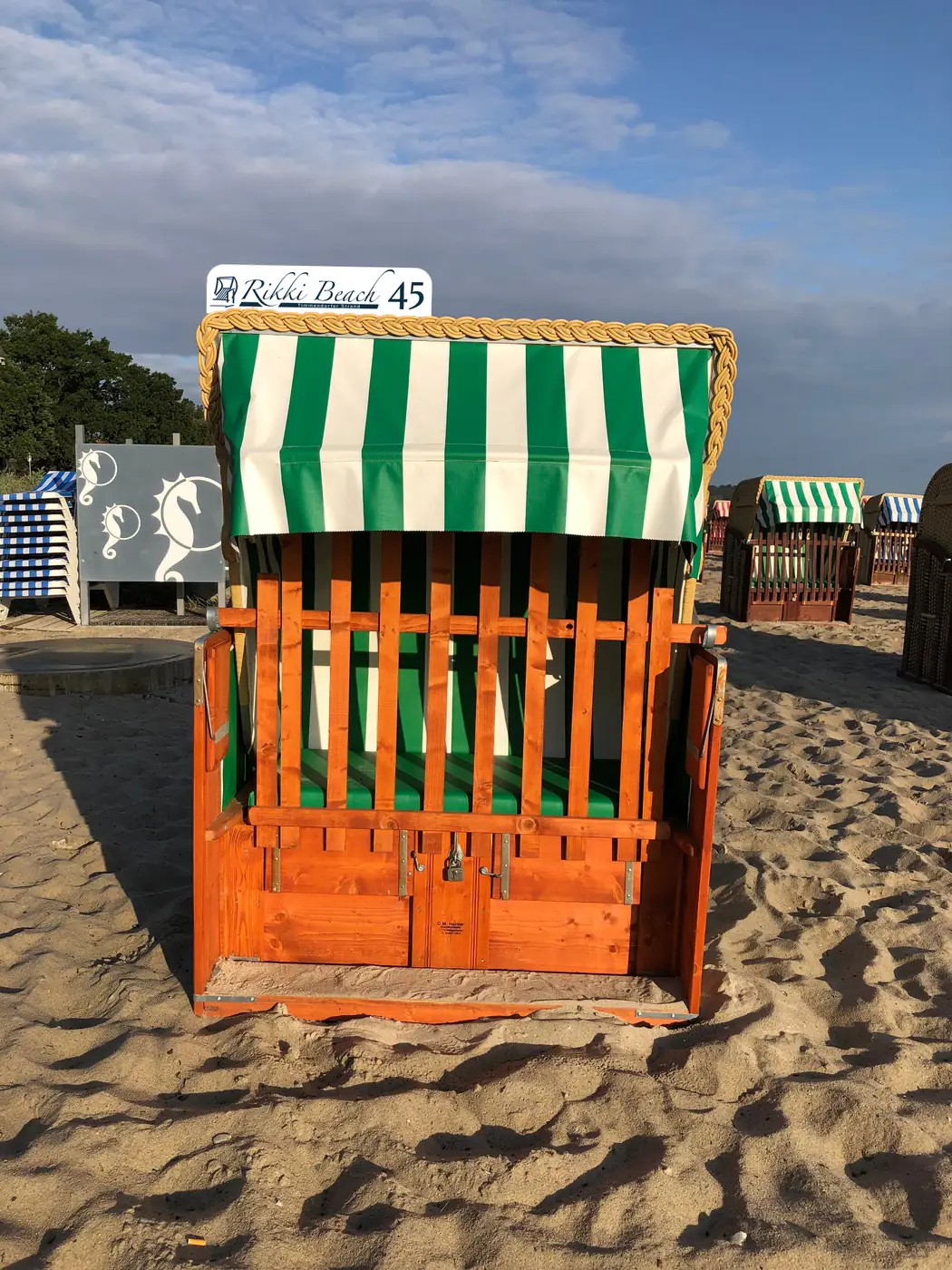 Grün-weiß gestreifter Strandkorb mit Nummernschild am Strand