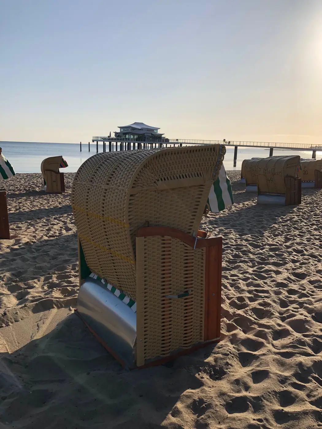 Strandkorb im Sand mit Blick auf das Meer und die Seebrücke